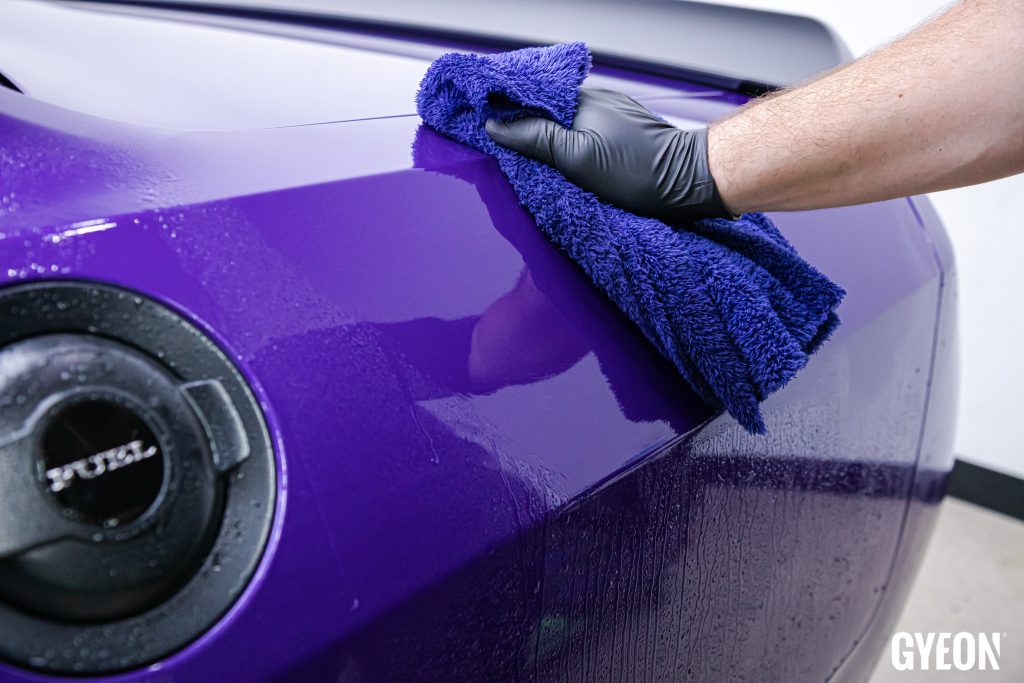 Purple car being dried with a microfiber towel